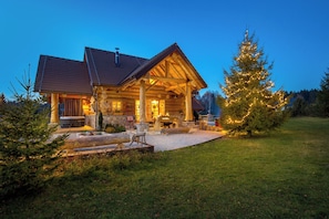 A log cabin with a stone foundation, wooden exterior, and a covered porch.