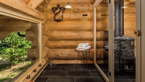 Interior de una cabaña de troncos con chimenea de piedra, un espejo y un perchero.