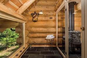 L’intérieur d’une cabane en rondins, avec une cheminée en pierre, un miroir et un porte-serviettes.