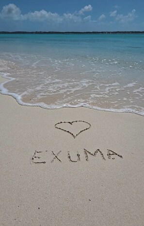 En strand formad som ett hjärta, och ordet ”EXUMA” skrivet i sanden.
