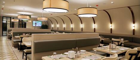 A restaurant with booth seating, tables with menus, and hanging lamps.