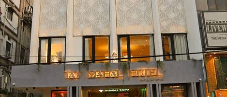 A hotel with a prominent sign reading 'TAJ MAHAL HOTEL' and a modern facade with patterned windows.