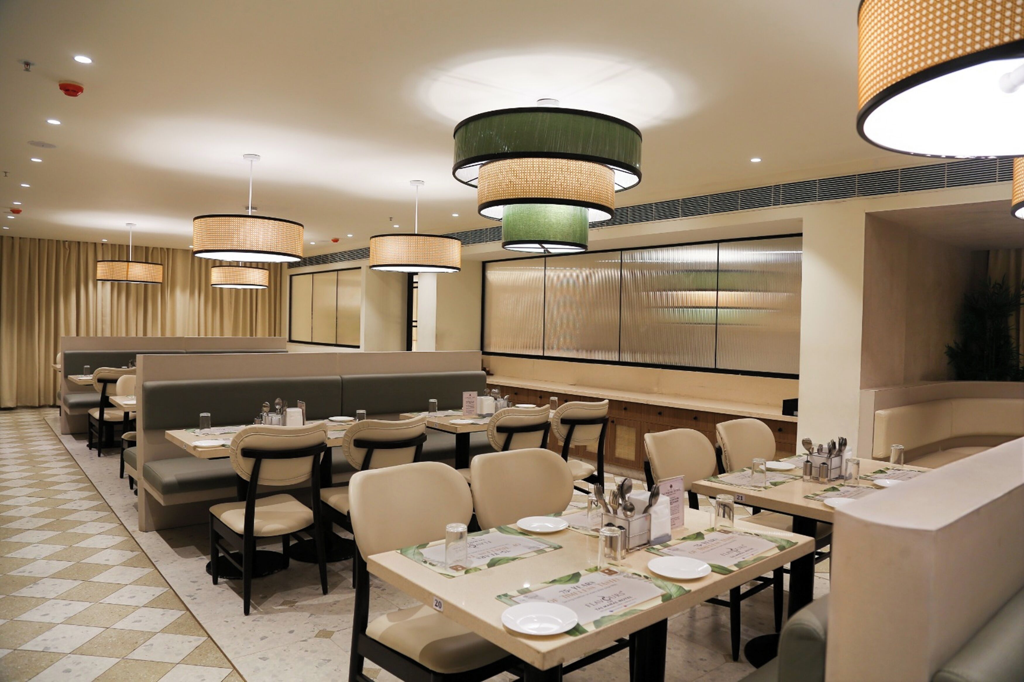 A restaurant with booths, tables, and hanging lamps.