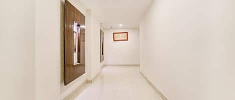 Un pasillo con paredes blancas, una puerta de madera y un cuadro enmarcado en la pared.
