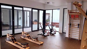 A spacious room with large sliding glass doors, a wooden climbing wall, and stationary exercise bikes. - Comfortable 2BR w/ Pool, Gym and BBQ | Free Parking (South Brisbane)