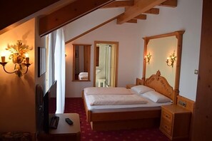 Een slaapkamer met een houten bed, nachtkastjes, een spiegel en een televisie.