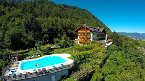 Un hotel con piscina rodeado de exuberante vegetación y montañas al fondo.