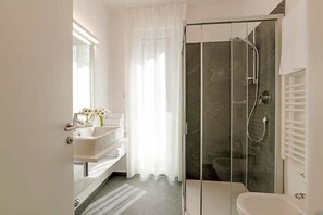 A modern bathroom with a glass-enclosed shower, a white sink, and a vanity with a mirror. - Residence Desiree (Merano)