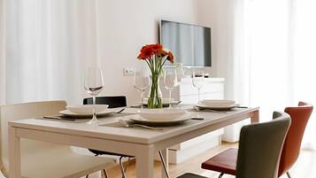 Una mesa de comedor dispuesta con platos, vasos y un jarrón de flores.