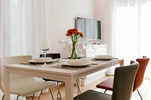 A dining table set with plates, glasses, and a vase of flowers. - Residence Desiree (Merano)