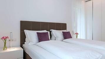 Una habitación de hotel moderna con una cama grande, una mesita de noche y una mesita auxiliar.