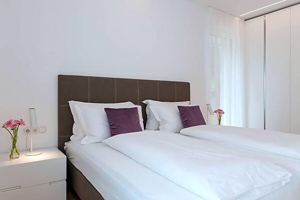 A modern hotel room with a large bed, a bedside table, and a nightstand. - Residence Desiree (Merano)