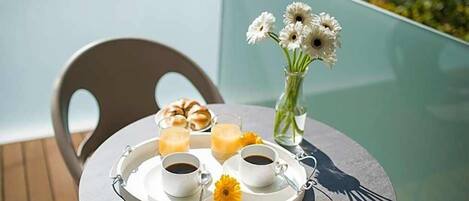 Una mesa con una bandeja de comida y bebidas, una silla y un florero con flores.