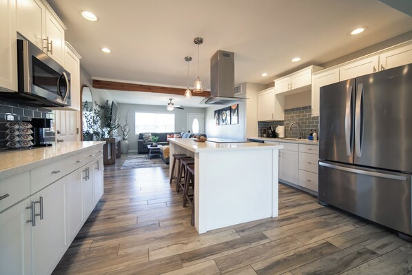 A modern kitchen with a central island, stainless steel appliances, and wooden flooring.