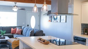 Une cuisine moderne dotée d’un îlot central, de luminaires suspendus et d’une cuisinière intégrée.