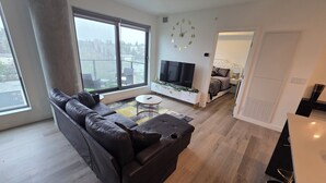 Uma sala de estar moderna com um sofá seccional, uma televisão e um espaço de jantar com mesa e cadeiras.