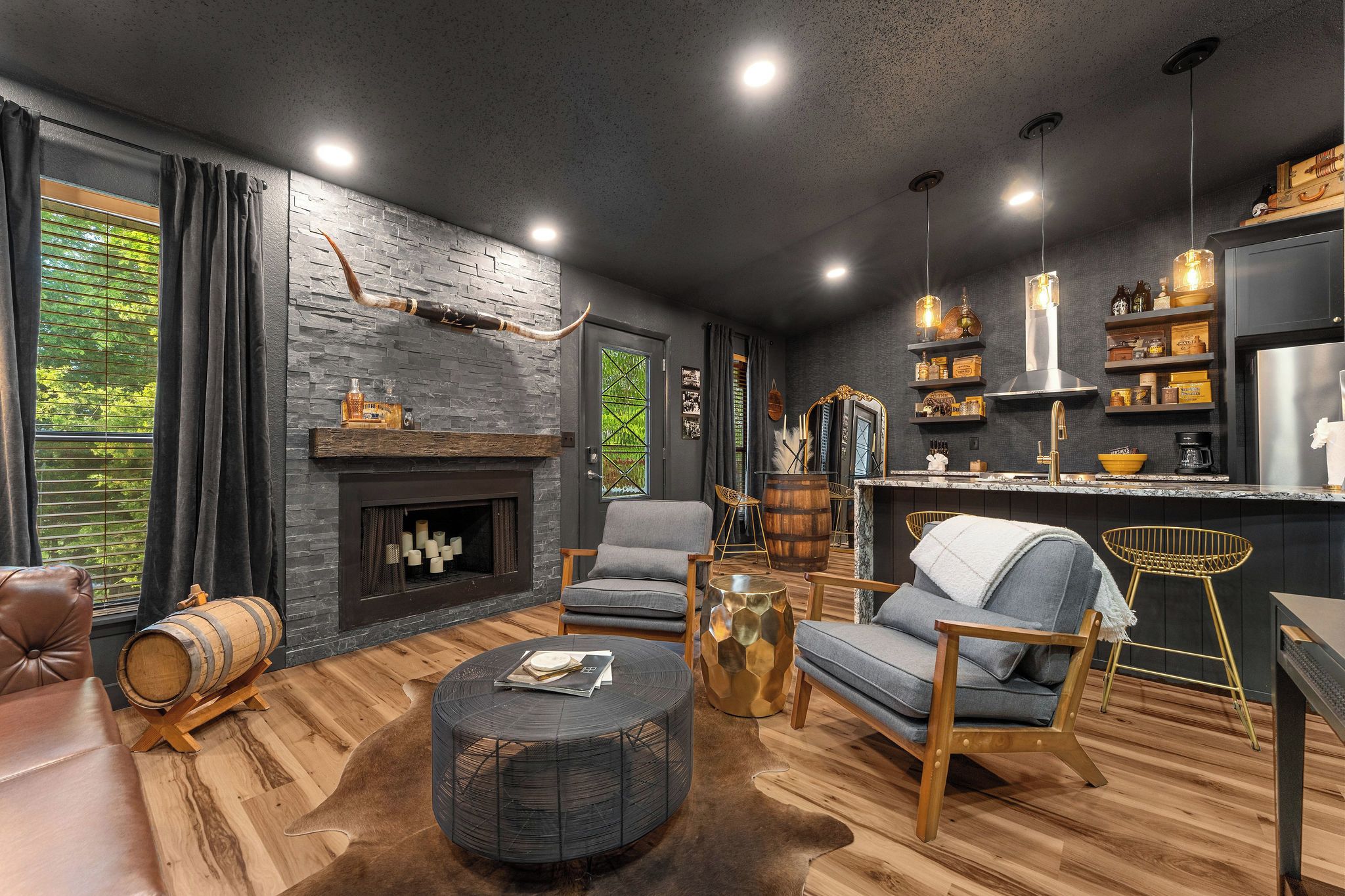 Una sala de estar moderna con chimenea, asientos y una zona de cocina.