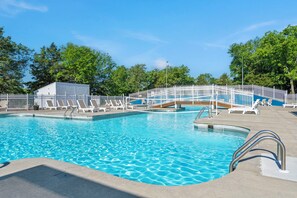 A swimming pool with multiple lanes, a white fence, and lounge chairs.