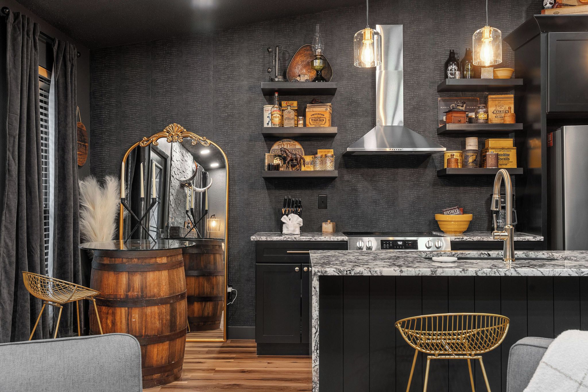 A modern kitchen with dark walls, wooden barrels, and a marble countertop.