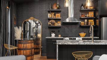 A modern kitchen with dark walls, wooden barrels, and a marble countertop.