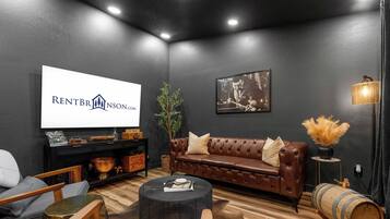 A modern living room with a dark wall, a leather sofa, a coffee table, and a television displaying 'RENTBR INSON.CO'.