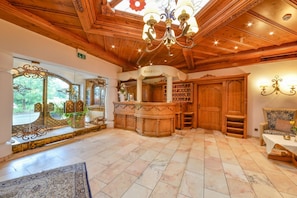A reception area with a wooden ceiling, a chandelier, a reception desk, and a view of the outdoors. - Doerr (Bad Laasphe)