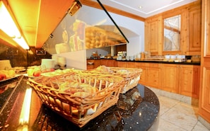 A buffet setup with wicker baskets containing various food items, a counter with kitchenware, and wooden cabinets in the background. - Doerr (Bad Laasphe)