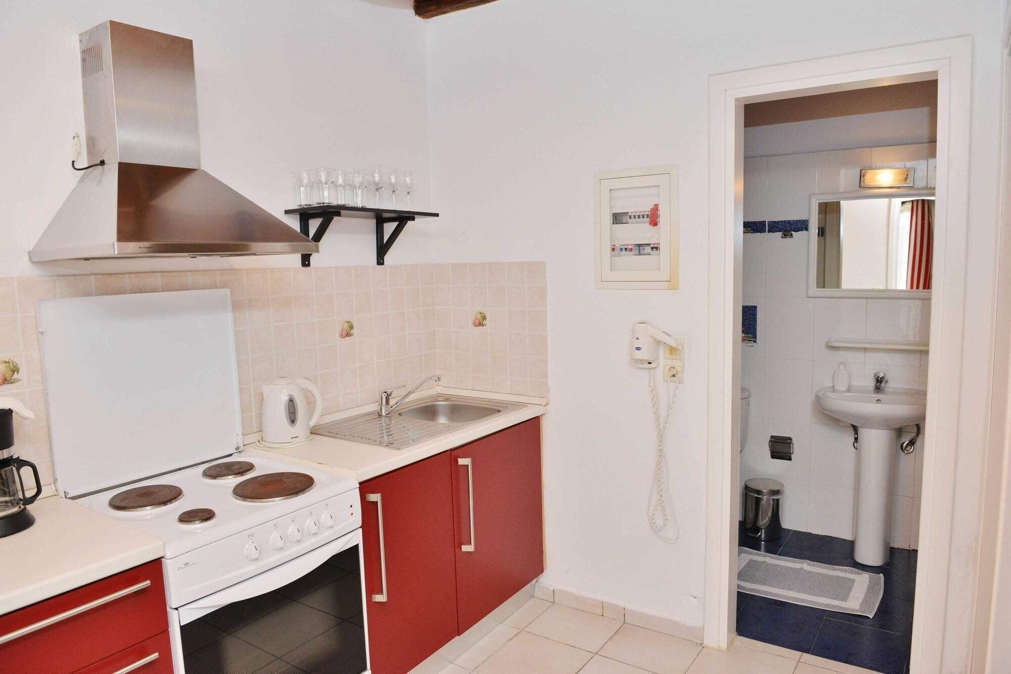 A compact kitchen with a stove, sink, and a small cabinet.