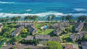 Un complejo turístico frente al mar con varias construcciones tipo bungalow, piscina y zona de estacionamiento.
