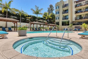 A swimming pool with lounge chairs, a covered seating area, and a multi-story building in the background. - Ocean & Marina View Condo with Balcony, Pool, Hot Tub & Gym (Oceanside)