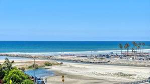Eine Küstenstraße mit Strand, Palmen und wolkenlosem, blauem Himmel.
