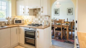Une cuisine moderne avec des meubles blancs, un four à micro-ondes, une cuisinière à gaz et un four traditionnel.