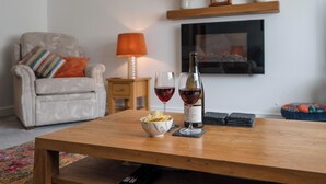 Un salon avec une table basse en bois, un canapé, un téléviseur, une cheminée et une lampe.
