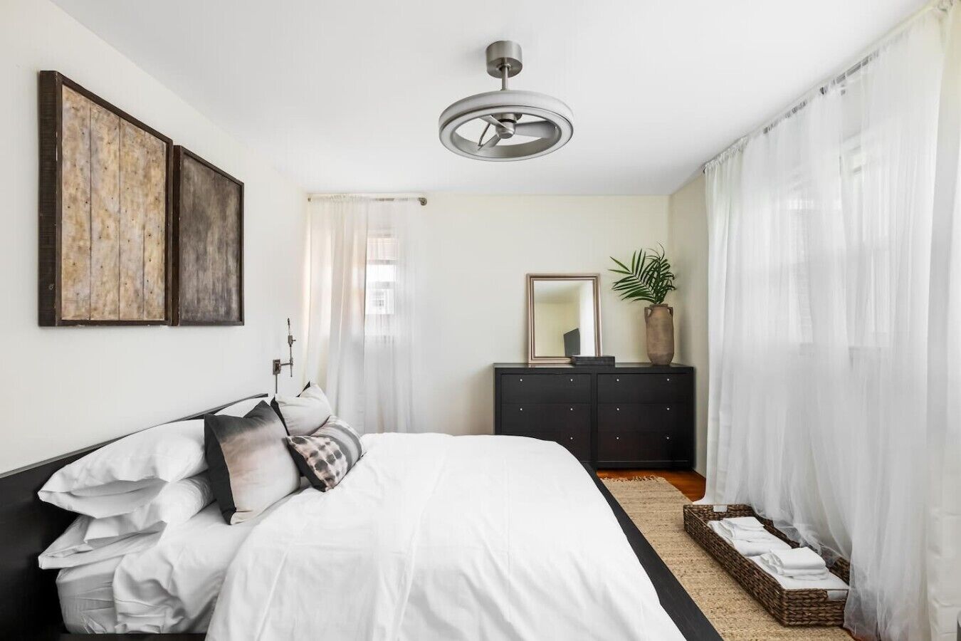 Ein Schlafzimmer mit Bett, Kommode, Spiegel und einer Pflanze.
