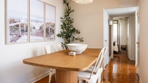 A dining area with a wooden table, white chairs, a large white bowl, and a hanging light fixture. - Light Filled 2BR w/ Balcony & 2 Free Parking (Arlington)