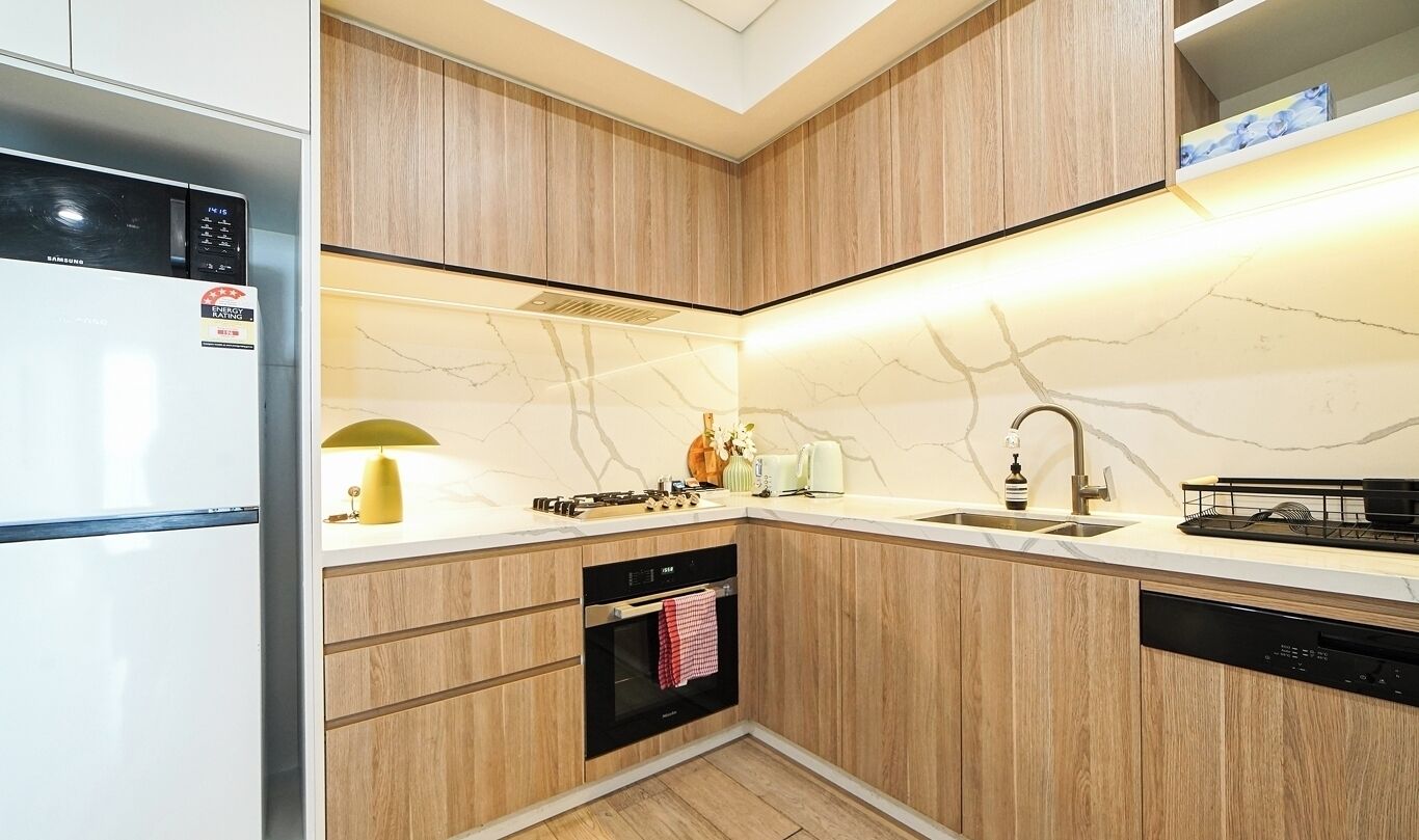 Une cuisine moderne avec des meubles en bois, un four encastré, un évier et un lave-vaisselle.