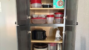 A kitchen pantry with storage shelves, a toaster, a slow cooker, and a coffee maker.