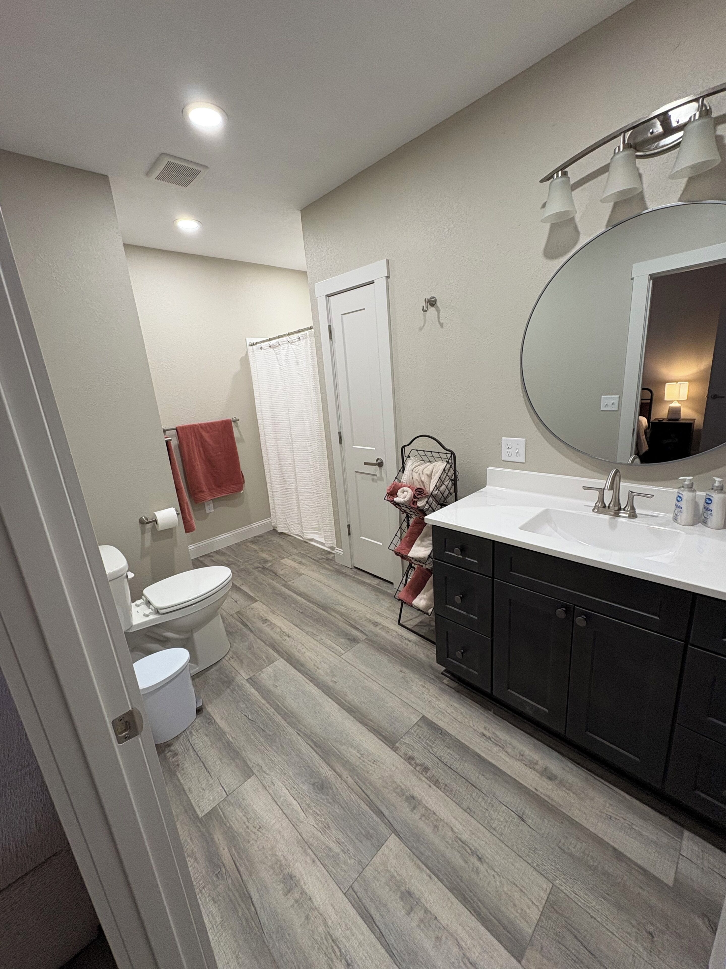 Un baño con inodoro, lavamanos, espejo y cortina de ducha.