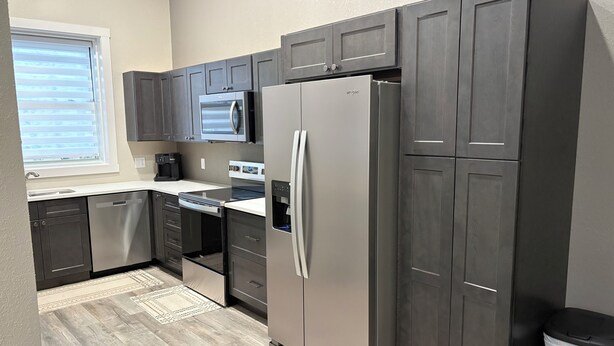 A modern kitchen with dark cabinetry, stainless steel appliances, and a built-in oven.