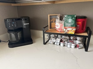 Une cuisine équipée d’une machine à café Keurig, d’un moulin à café, d’une cafetière et d’un compartiment de rangement pour les grains de café.