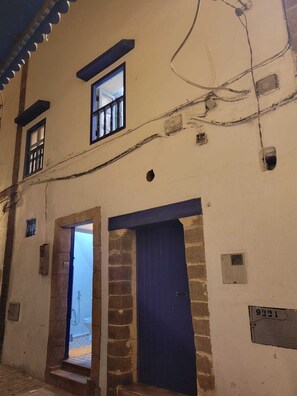 Un bâtiment avec une porte bleue et une fenêtre, une plaque d’immatriculation bien visible et une structure en briques.