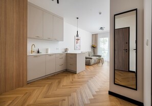 Eine moderne Küche mit hellen Schränken, einem Fischgrätparkett und einem großen Spiegel an der Wand.