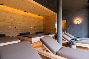 A spa room with wooden walls, multiple massage tables, and a large pillar. - Berghotel Schopfenhof (Dobbiaco)