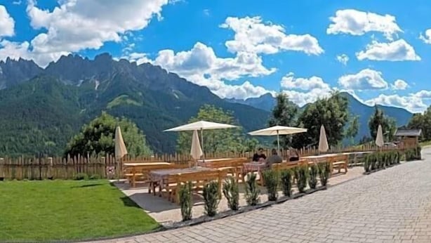 A playground with a slide, swings, and a fenced area. - Berghotel Schopfenhof (Dobbiaco)