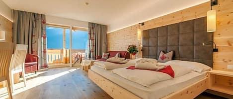 A bedroom with a large bed, a wooden headboard, a balcony, and a view of the sky.
