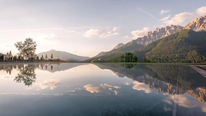 A tranquil lake with clear reflections, surrounded by mountains and trees. - Berghotel Schopfenhof (Dobbiaco)