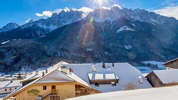 Paisagem montanhosa com pico banhado pelo sol, telhado coberto de neve e um edifício com placa.