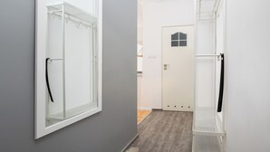 En gang med en grå væg, en hvid dør med et vindue og en hvid metalkasseskab.