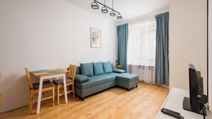 En stue med sofa, bord, stole, et fjernsyn og en loftlampe.