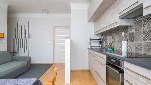 Eine moderne Küche mit Einbauofen, ein Essbereich mit einer Bank und ein Wohnzimmer mit einer Couch.